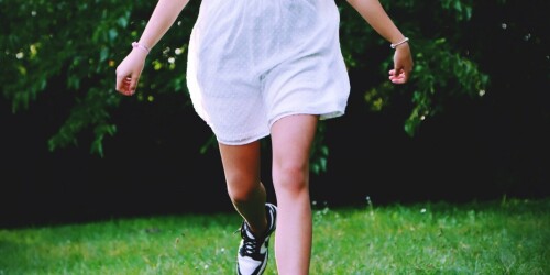 Dziewczynka w białej sukience biegnie po łące.