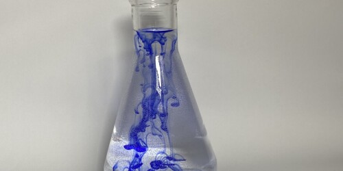 Kolba chemiczna z wodą. W wodzie znajduje się niebieski atrament.