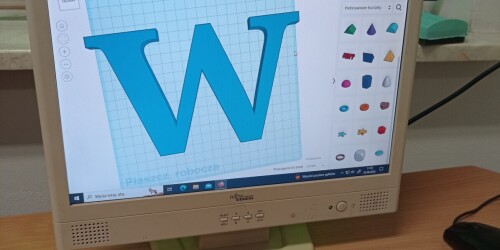 Niebieska litera W na ekranie komputera.