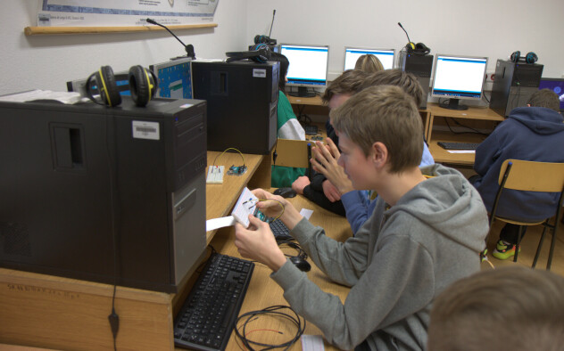 Uczniowie w pracowni komputerowej pracują na poprawnym złożeniem obwodu z mikrokontrolerem.