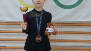 Dziewczynka w czarnym stroju z medalem i pucharem