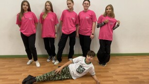 Uczennice klasy 6a pozują w różowych koszulkach zespołu tanecznego a uczeń leży